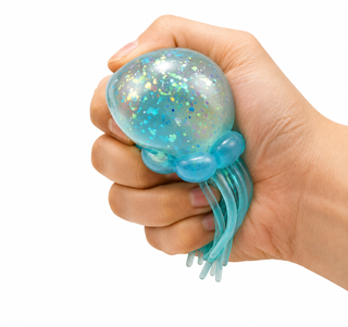 A hand squeezing a translucent blue jellyfish stress toy with iridescent glitter inside, shown against a plain white background.