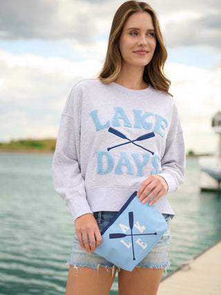 Woman wearing a 'Lake Days' sweatshirt by a lake