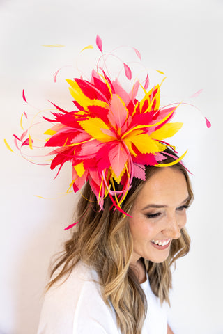 Woman wearing a vibrant, colorful headpiece against a white background