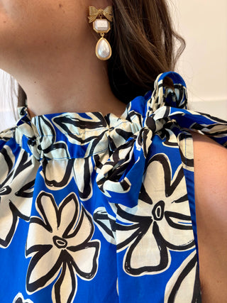 Close-up of a person wearing a blue floral dress with bow straps.