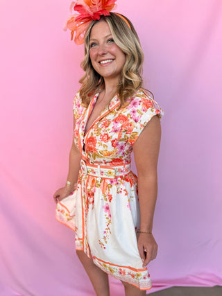 Woman wearing a floral dress and headpiece against a pink background
