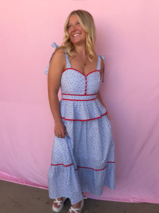 Woman wearing a blue stripe dress with red trim against a pink background