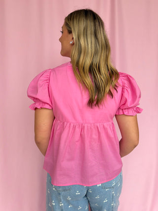 Woman wearing a pink blouse with puff sleeves against a pink background