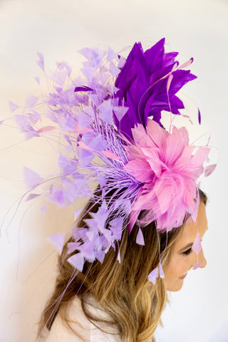Woman wearing a decorative headpiece with purple and pink feathers on a white background