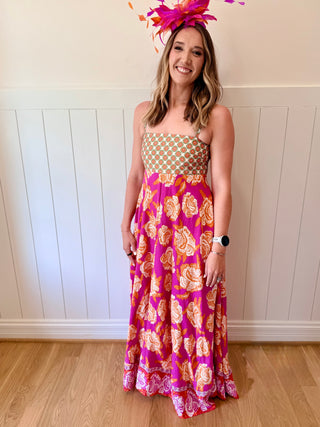 Woman wearing a colorful floral dress with a white wall background