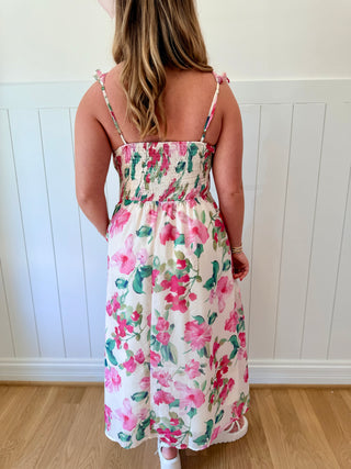 Woman wearing a floral dress with a white wooden panel background