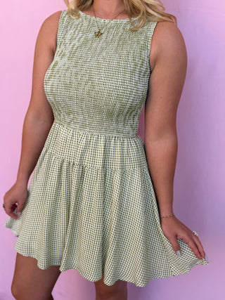 Woman wearing a green checkered dress against a pink background