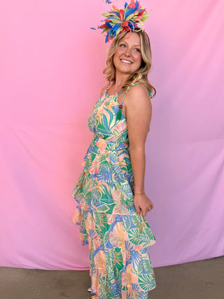 Woman wearing a colorful floral dress and headpiece against a pink background