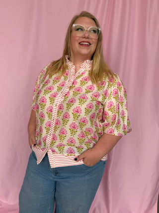 Person wearing a floral blouse with a pink background