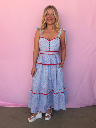 Woman wearing a blue stripe dress with red trim against a pink background