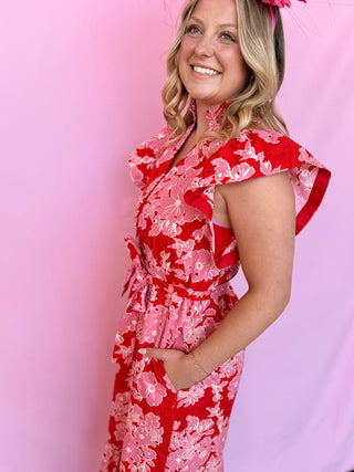 Woman wearing a red floral dress against a pink background