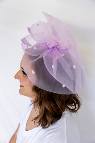 Woman wearing a light purple decorative hat with a white background