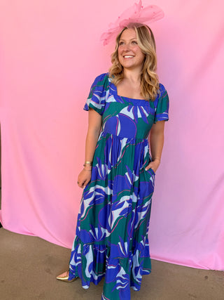 Woman wearing a blue and green patterned dress against a pink background