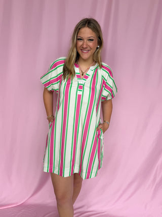 Woman wearing a striped dress against a pink background