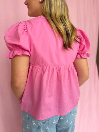Person wearing a pink blouse with puffed sleeves against a pink background