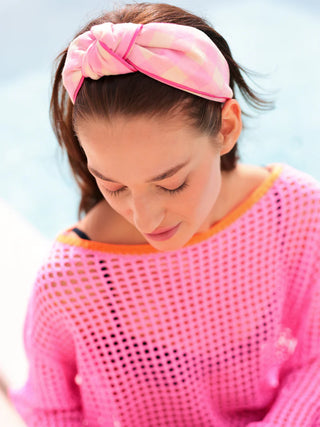 Woman wearing a pink headband and sweater against a light blue background