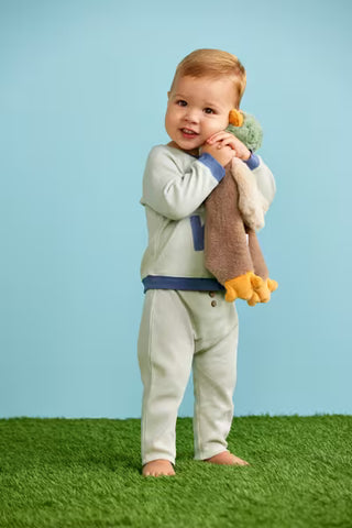 Child holding a toy in front of a blue background
