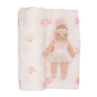 Doll in a tutu lying on a floral-patterned blanket