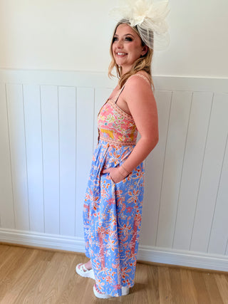 Woman wearing a colorful floral dress with a white wall background