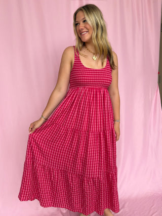 Woman wearing a red checkered dress against a pink background