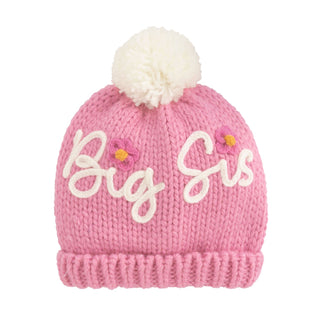 Pink knit hat with 'Big Sis' text and white pom-pom on a white background