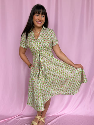 Woman wearing a green patterned dress against a pink background