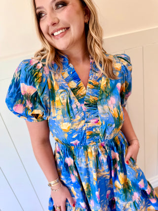 Woman wearing a blue floral dress against a white wall
