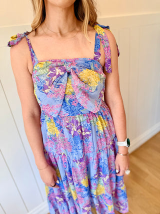 Person wearing a colorful floral dress with a plain background