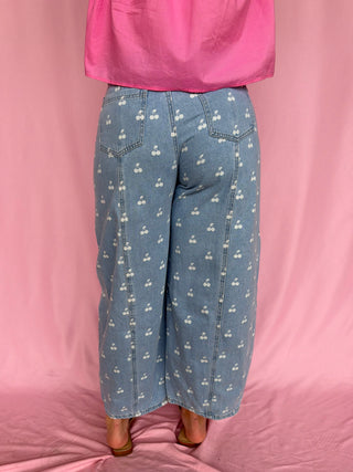 Person wearing blue jeans with white patterns on a pink background