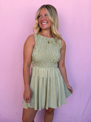 Woman wearing a green checkered dress against a pink background