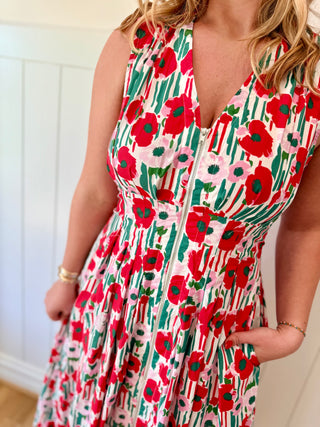 Woman wearing a floral dress with red poppies and green leaves.