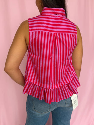 Person wearing a red and white striped sleeveless top with ruffles on a pink background