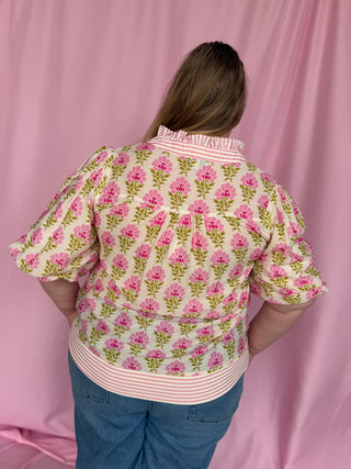 Person wearing a floral blouse with a pink background