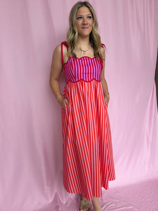 Woman wearing a red and white striped dress against a pink background