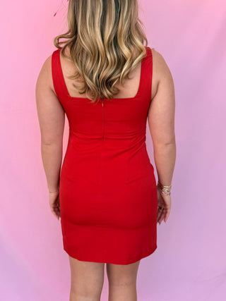Person wearing a red dress against a pink background