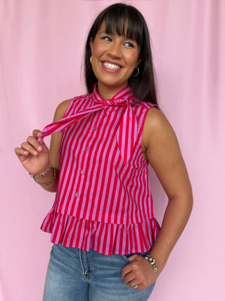 Woman wearing a pink and white striped top against a pink background