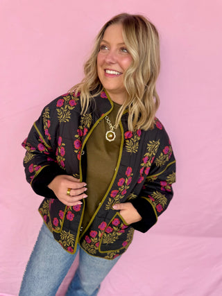 Woman wearing a floral patterned jacket against a pink background