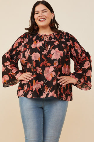 Woman wearing a floral blouse with bell sleeves on a beige background