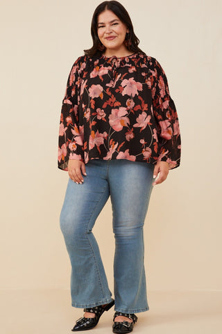 Woman wearing a floral blouse and jeans on a beige background