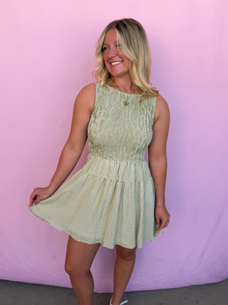 Woman wearing a green checkered dress against a pink background