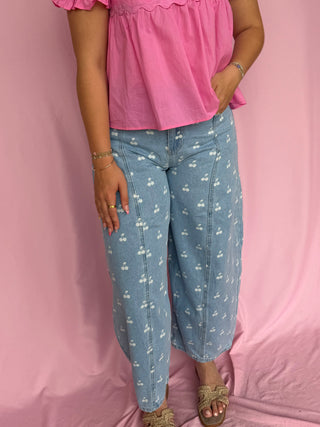 Person wearing a pink top and blue floral pants against a pink background