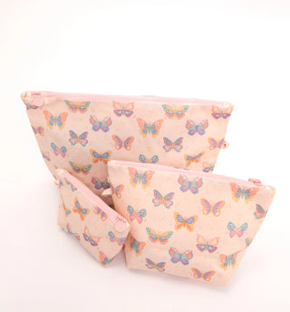 Three soft fabric zip pouches in a matching set, featuring a pastel pink background with a colorful butterfly print in shades of blue, purple, orange, and green.