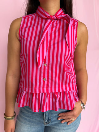 Person wearing a red and white striped blouse with ruffled details on a pink background