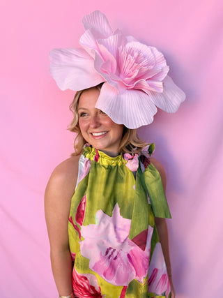 Woman wearing a large floral hat against a pink background