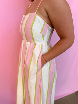 Person wearing a colorful striped dress against a pink background