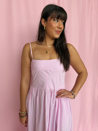 Woman wearing a pink and white striped dress against a pink background