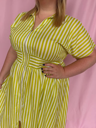 Person wearing a yellow and white striped dress against a pink background