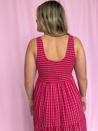 Woman wearing a pink checkered dress against a pink background