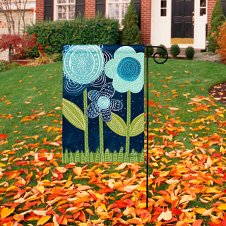 Decorative garden flag with floral design on a lawn with autumn leaves