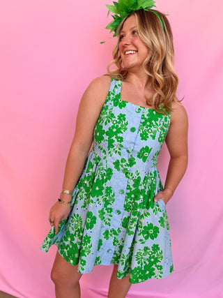 Woman wearing a green and blue floral dress against a pink background